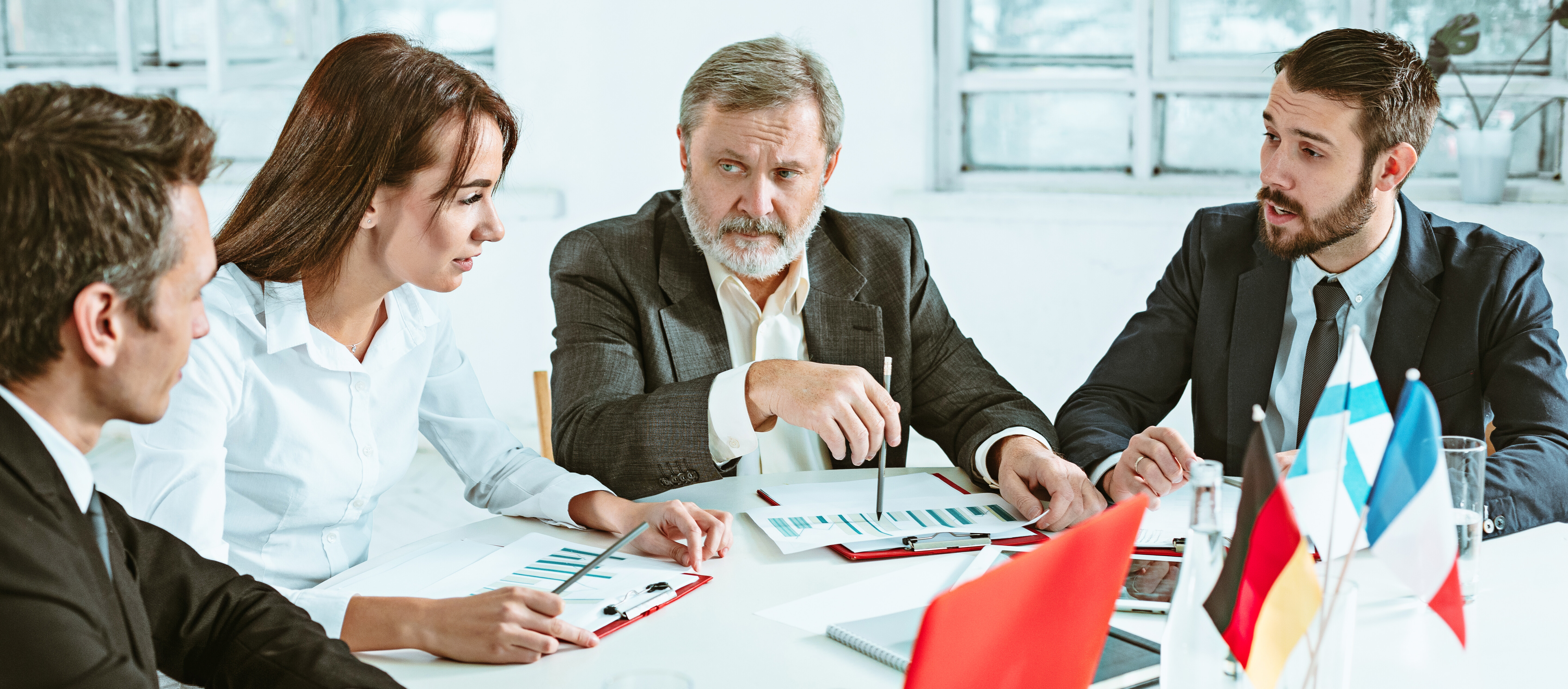 Internationale Geschäftsleute besprechen Berichte und Diagramme bei einem formellen Meeting.