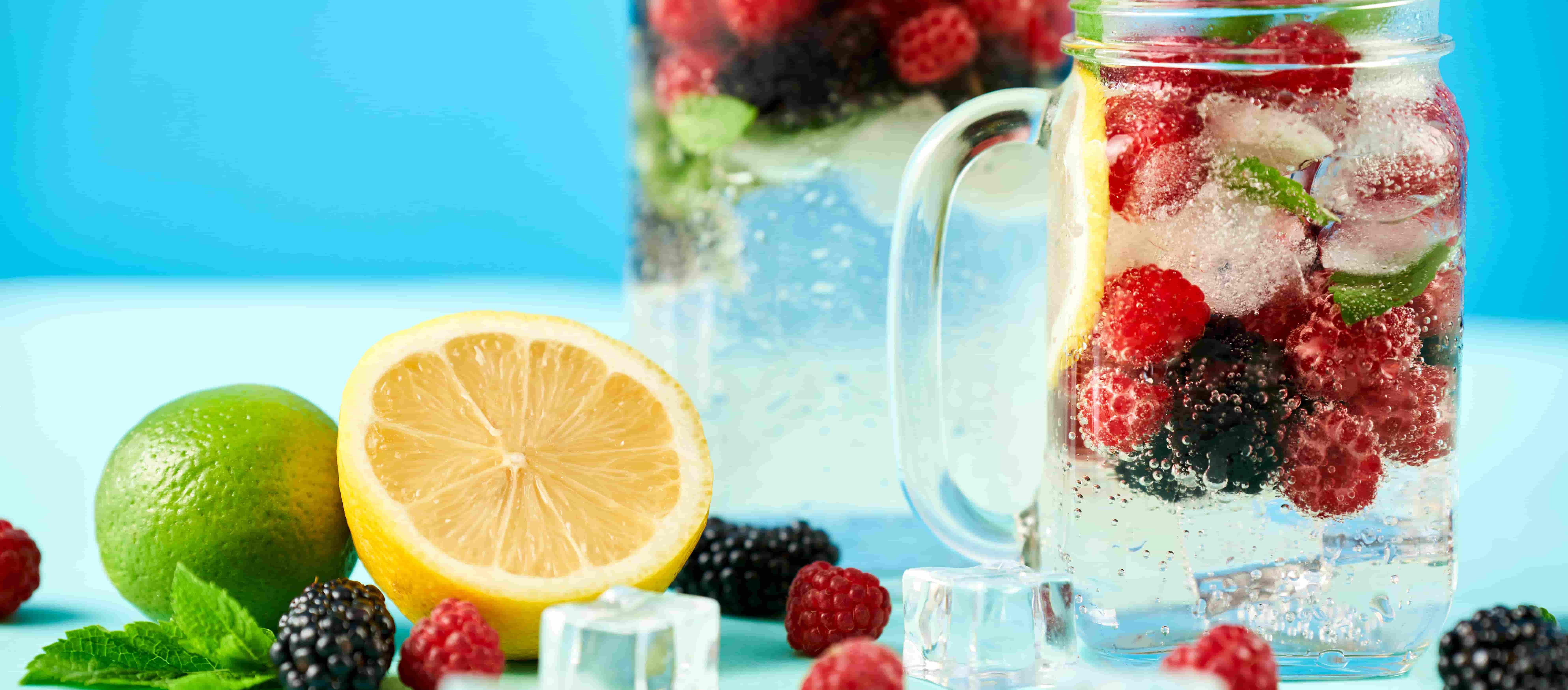 Kalte Getränke mit Eiswürfeln, verschiedenen Früchten und Minze