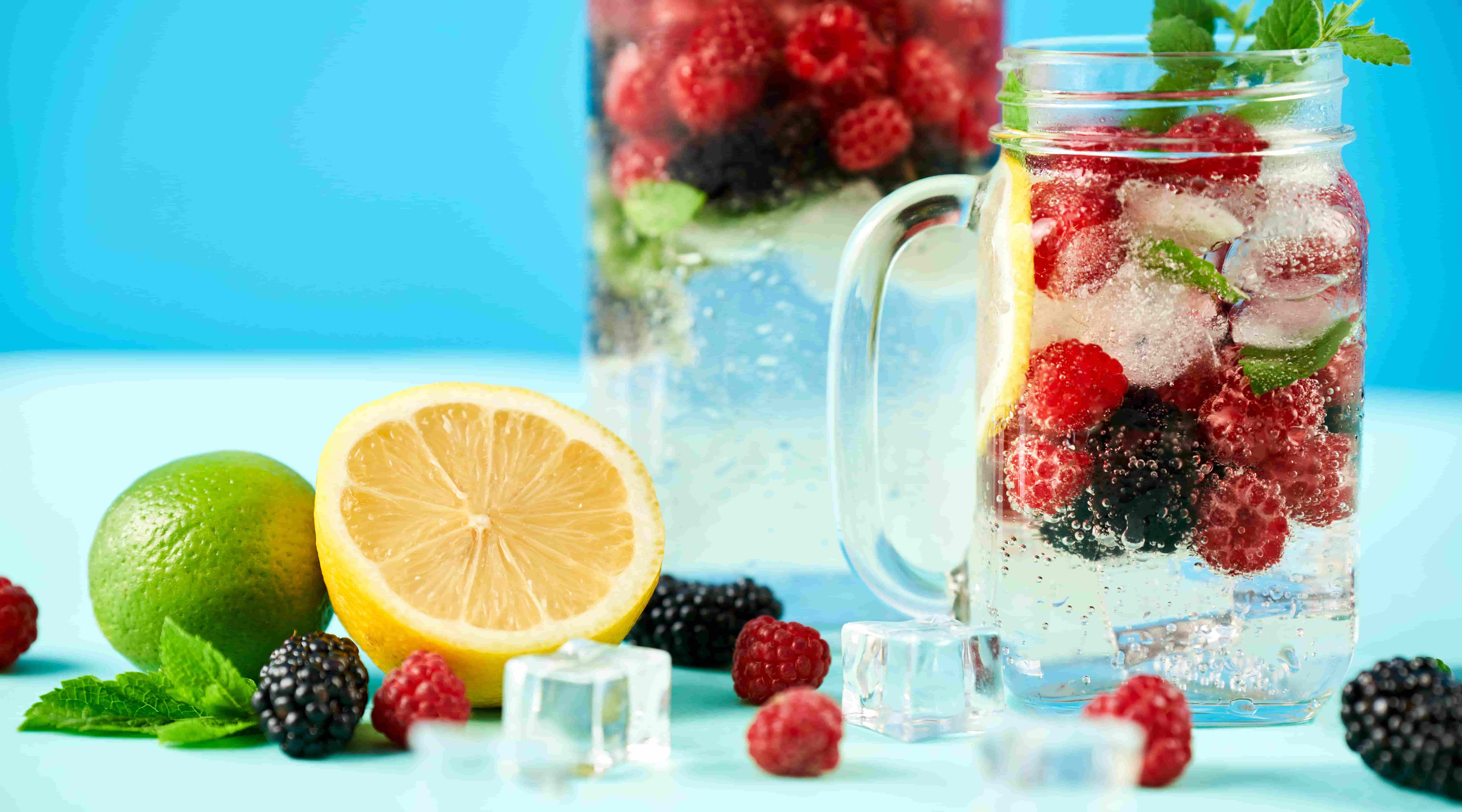 Kalte Getränke mit Eiswürfeln, verschiedenen Früchten und Minze