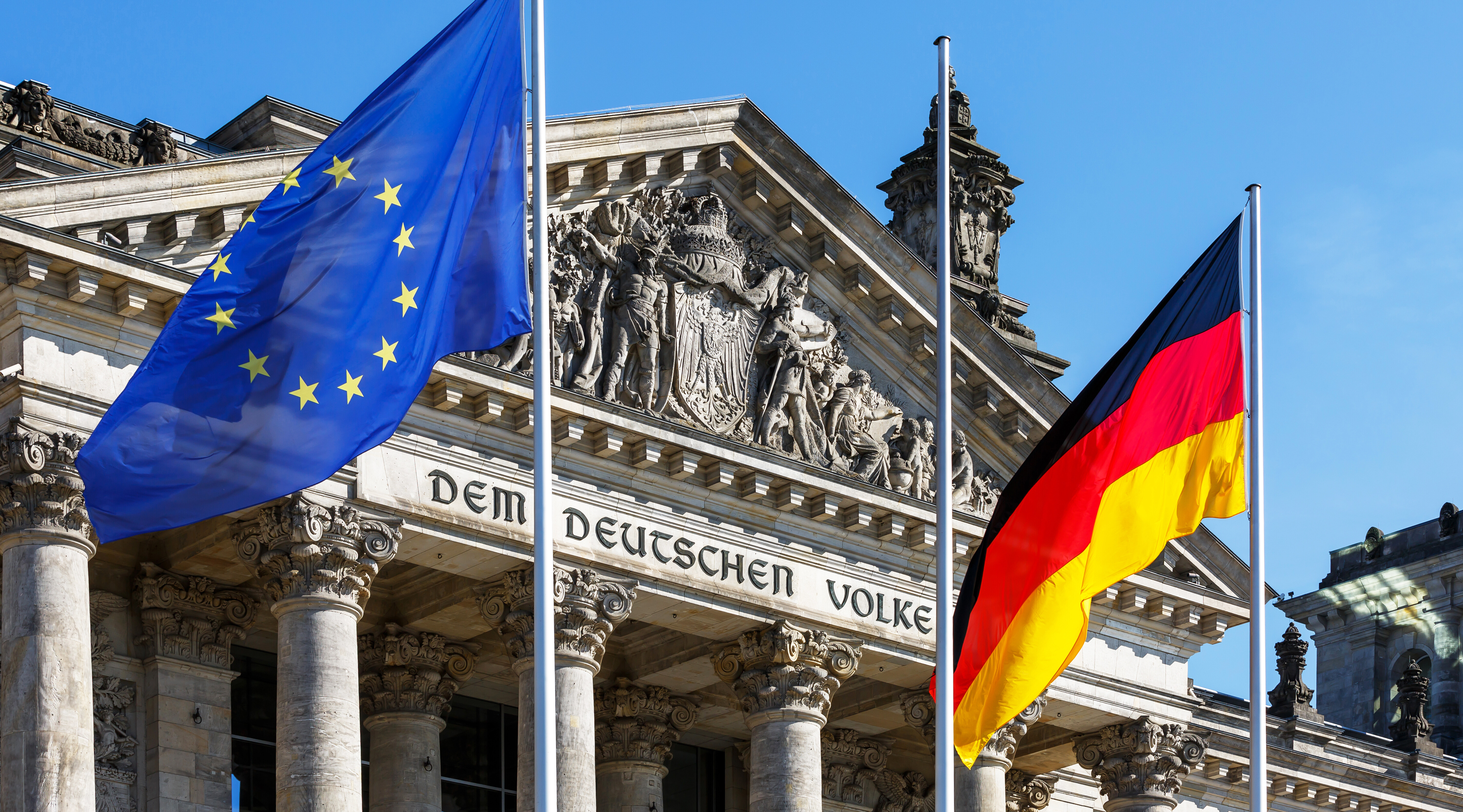 EU- und deutsche Flagge wehen vor dem Reichstagsgebäude in Berlin.