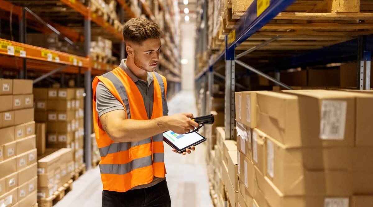 Ein Logistik-Mitarbeiter scannt im Lager Verpackungen.