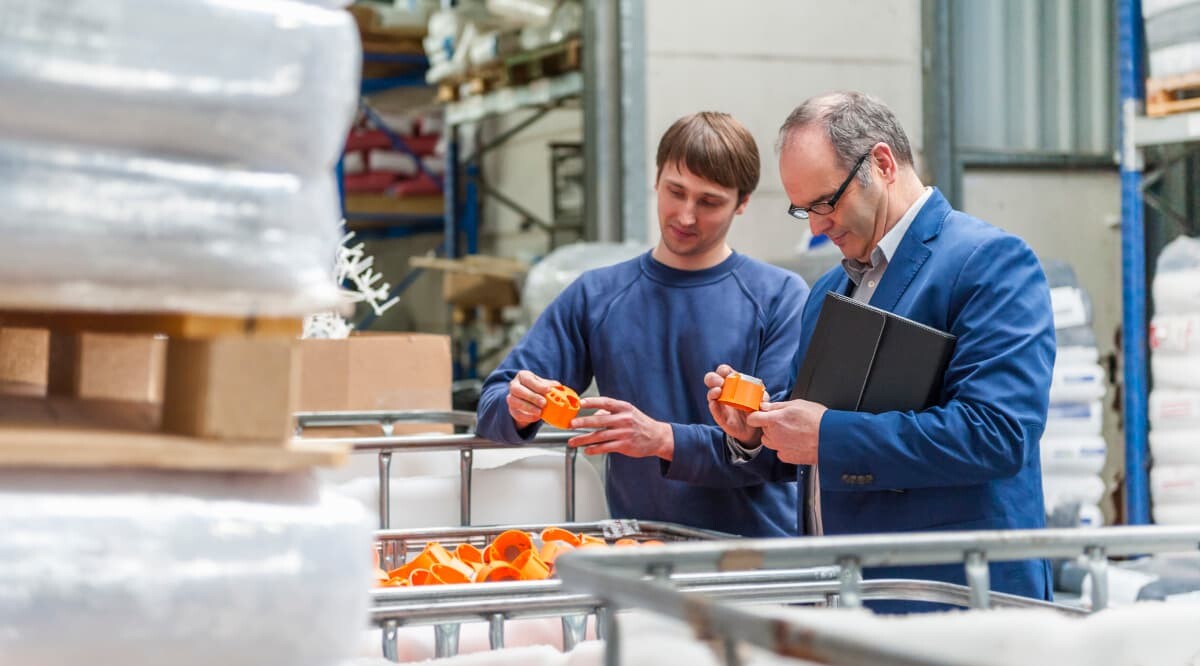 Manager und Arbeiter im Lager einer Kunststofffabrik bei der Produktkontrolle