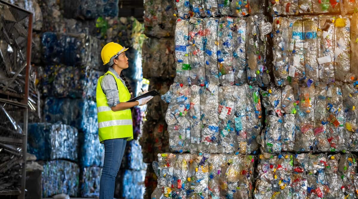 Arbeiterin steht vor Recyclingmaterial