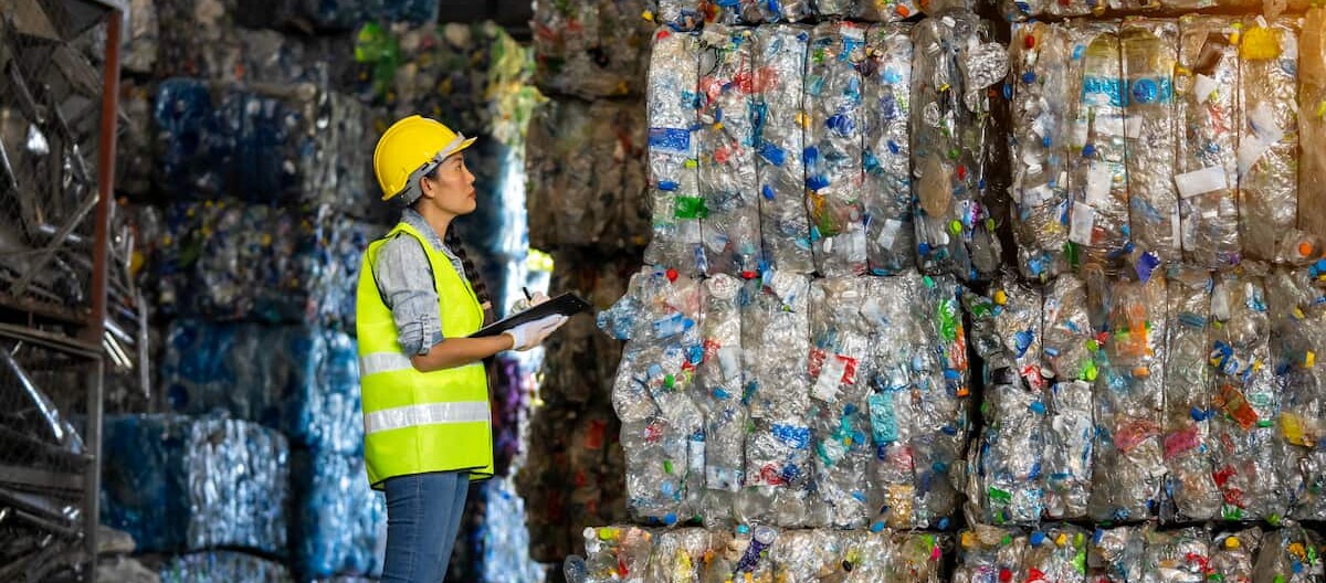 Arbeiterin steht vor Recyclingmaterial