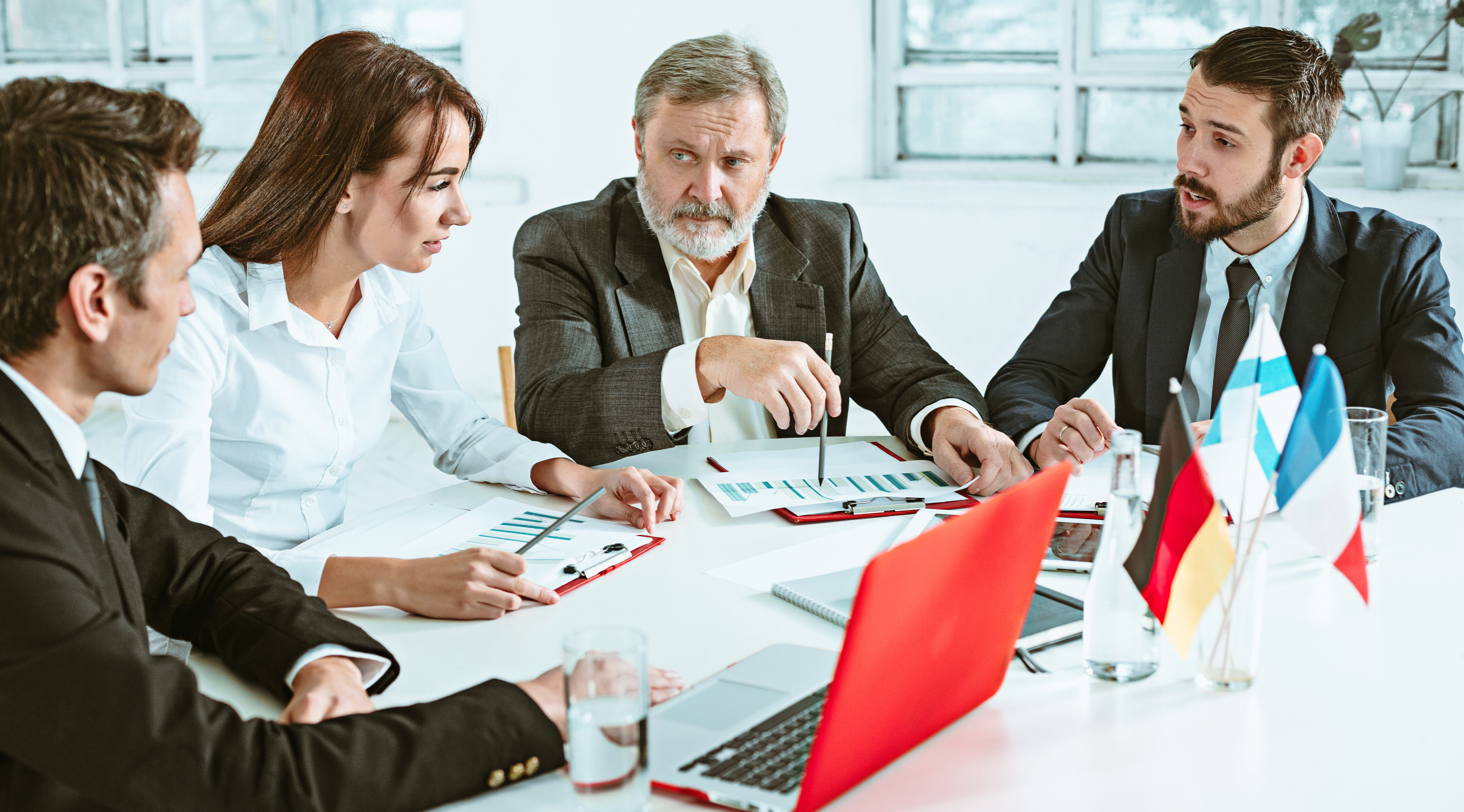 Internationale Geschäftsleute besprechen Berichte und Diagramme bei einem formellen Meeting.
